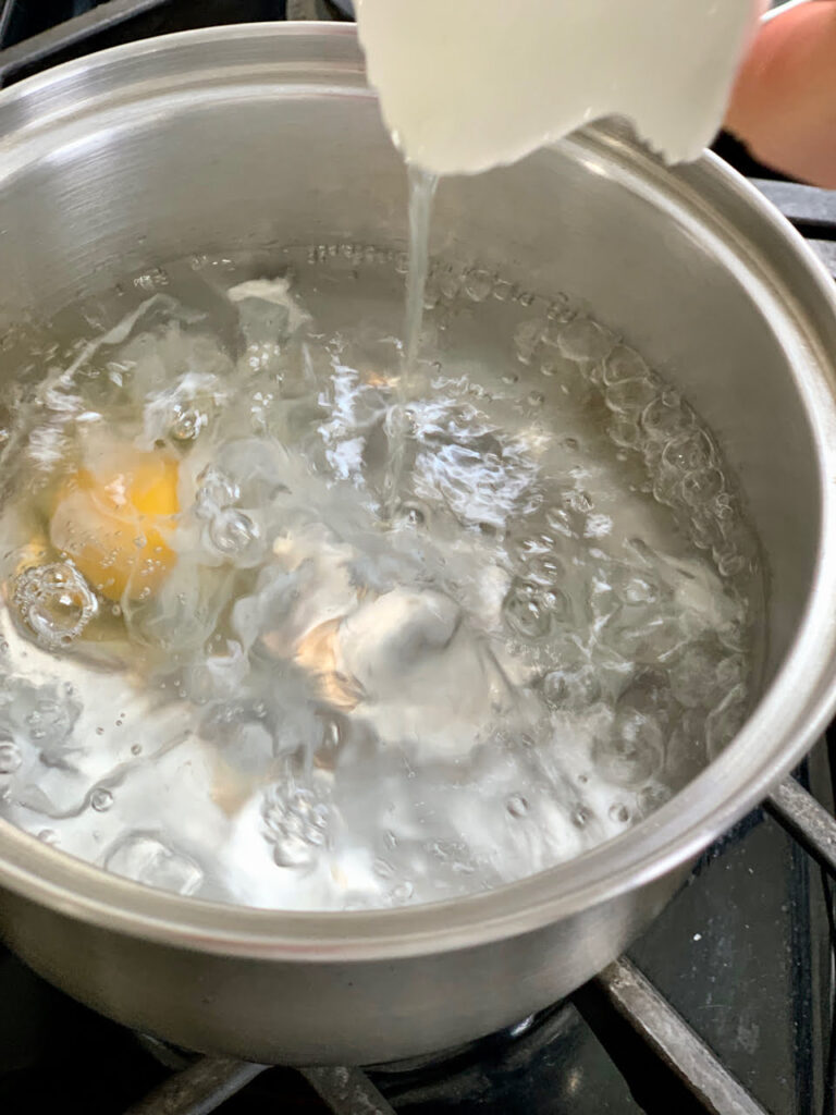 Egg in boiling water to poach.