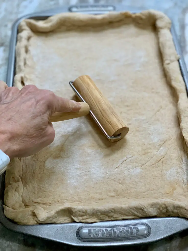 Rolling pizza dough into a baking sheet pan