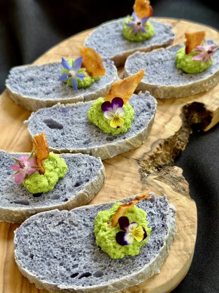 Crostini Appetizer of Purple Sweet Potato Bread with Pea Pesto and Edible Flowers